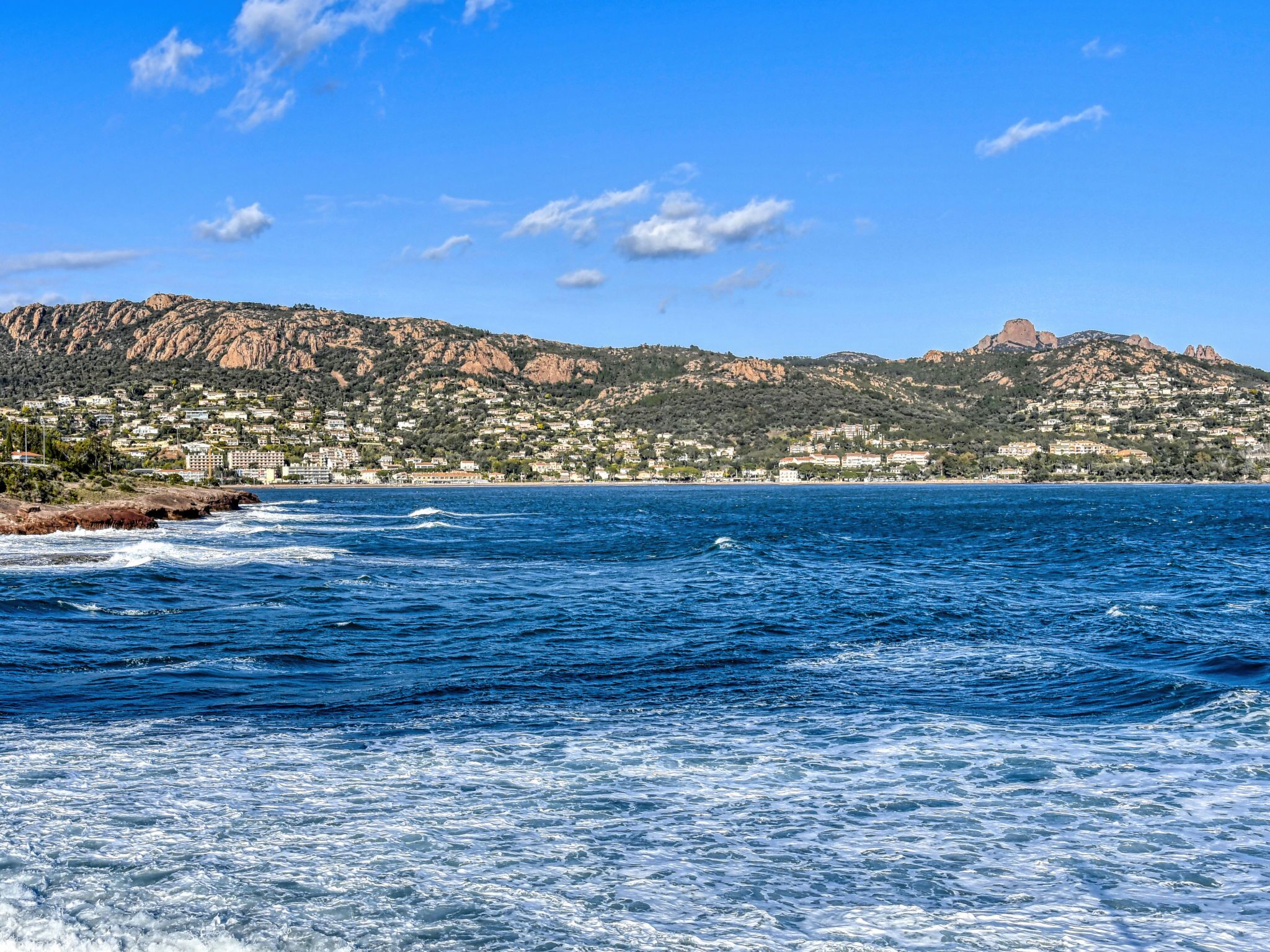 A coastal town with a mountain in the background and a view of the sea.