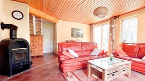 Ein Wohnzimmer mit einem roten Ledersofa, einem Holztisch und einem schwarzen Kaminofen.