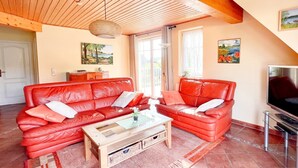 Ein Wohnzimmer mit roten Ledersofas, einem Holztisch und einem Fernsehschrank.
