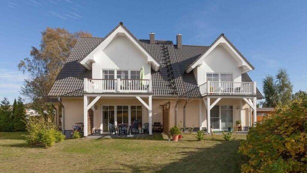 Ein zweistöckiges Haus mit einem Balkon im ersten Stock und einer überdachten Veranda im zweiten Stock.