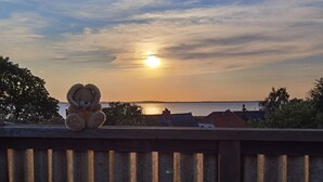 A sunset over a body of water with a teddy bear on a railing.