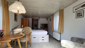 A compact hotel room with a bed, a desk, a chair, a table, and a television.