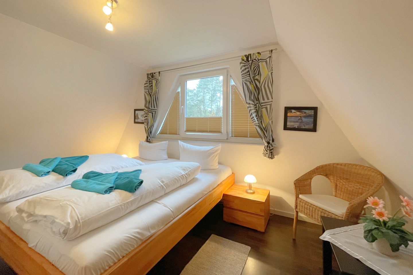 A bedroom with a bed, a nightstand, a chair, and a window with curtains.