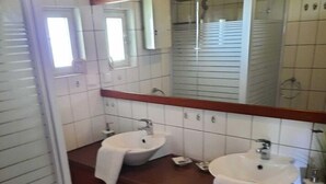 Un baño con dos lavamanos, un espejo y armarios de madera.