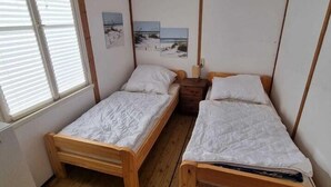 Una habitación pequeña con dos camas de madera, una ventana y una pared decorada con imágenes.