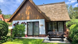 A wooden house with a thatched roof, large windows, and a bench in the front garden. - Strandstrasse - "Vacation in the vacation home Min Hüsung: relaxation and adventure on the Baltic Sea!" (Loddin)