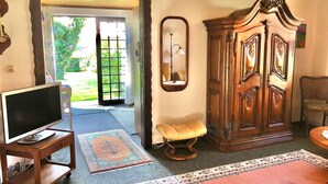 A living room with a television on a stand, a wooden cabinet, a bench, and a rug. - Strandstrasse - "Vacation in the vacation home Min Hüsung: relaxation and adventure on the Baltic Sea!" (Loddin)