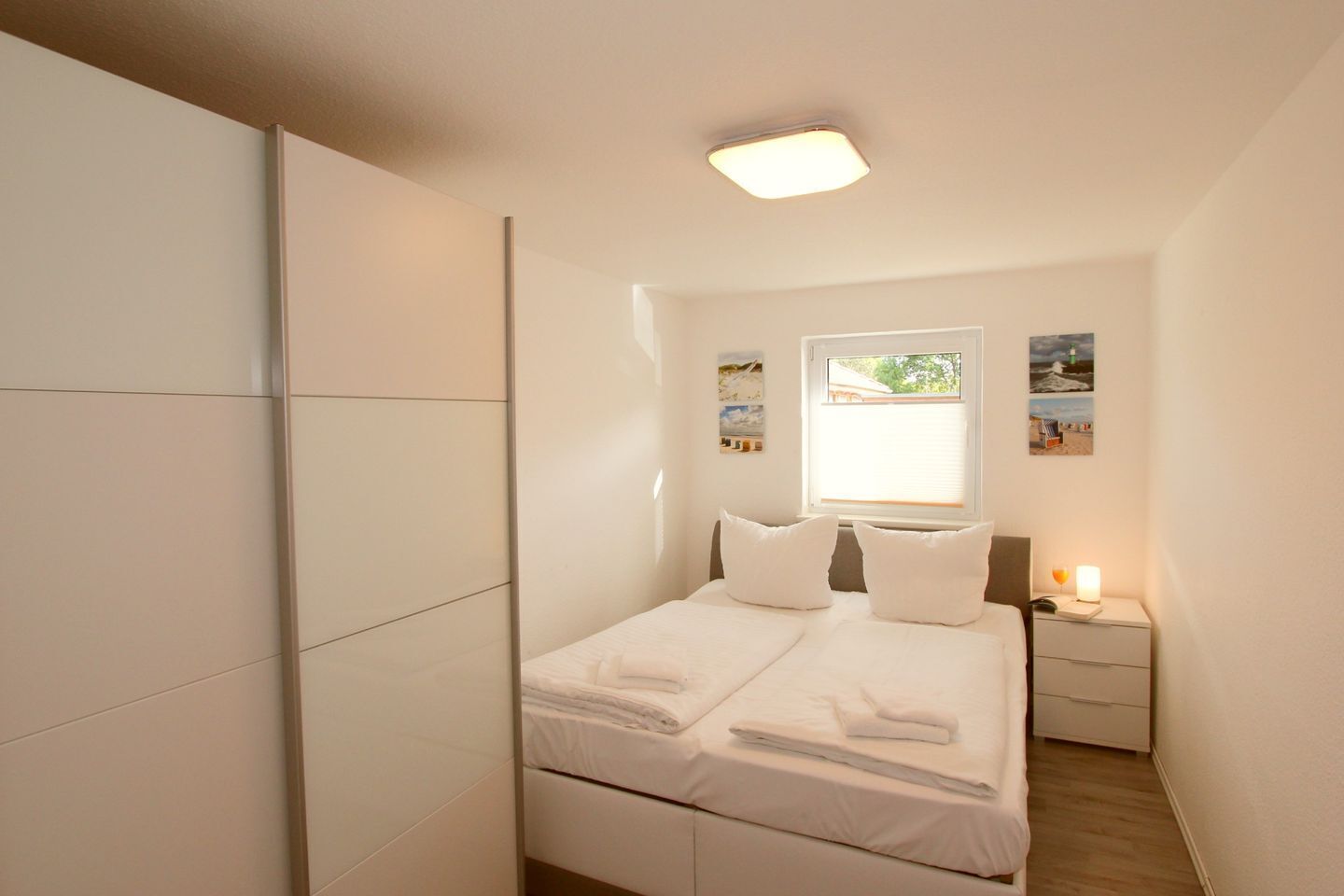 A bedroom with a bed, bedside table, and a window with a view.