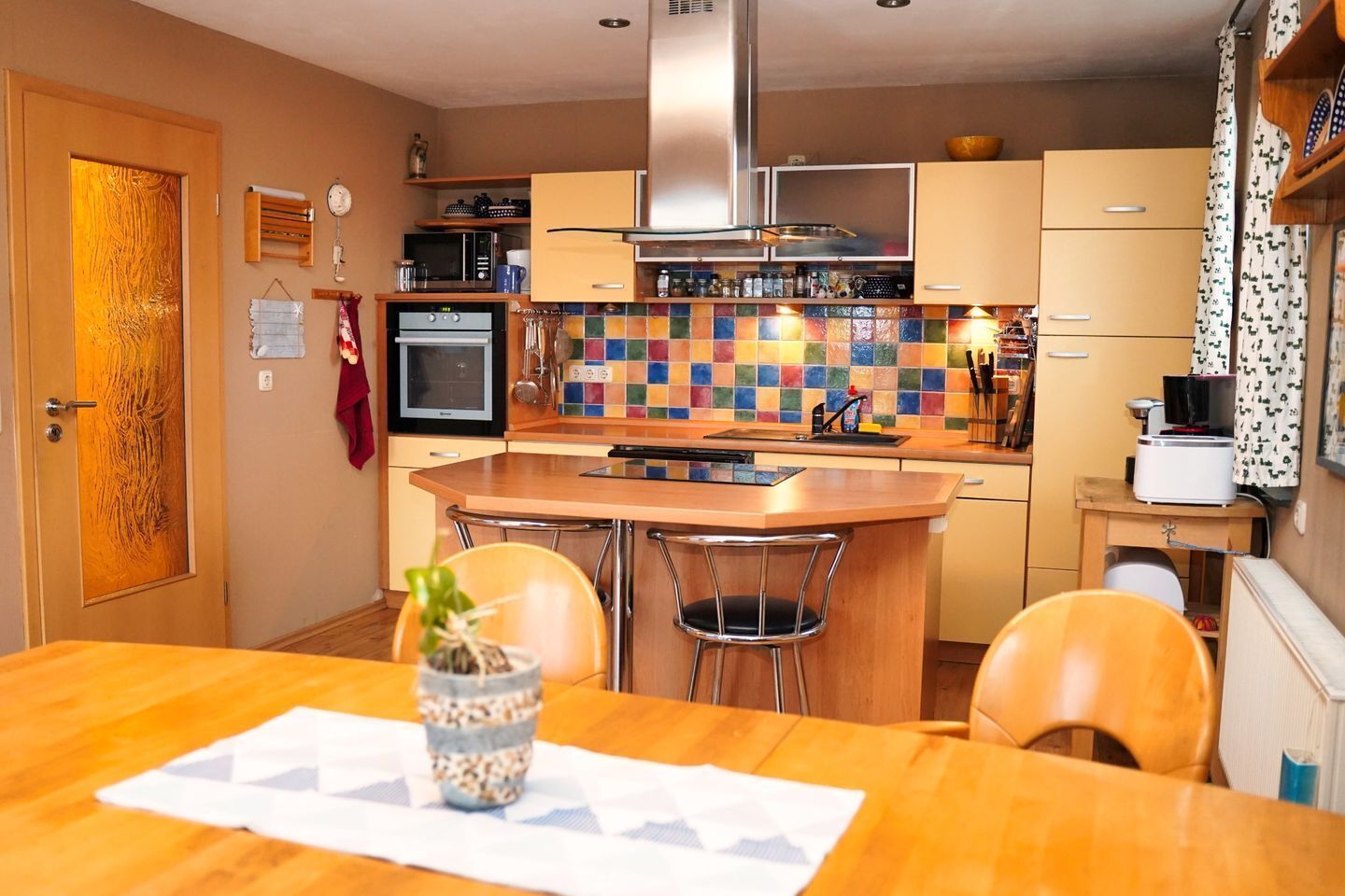 Una cocina compacta con una isla central, microondas, horno y una variedad de utensilios sobre la encimera.