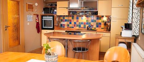 Una cocina compacta con una isla central, microondas, horno y una variedad de utensilios sobre la encimera.
