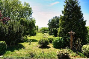 A garden with various trees and shrubs, a wooden birdhouse, and a clear sky. - Fischerstrasse - Moderne 3-zimmer Ferienwohnung "to'n Appelboom" mit Meerblick zum Achterwasser (Ückeritz)