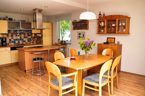 A modern kitchen with a central island, wooden chairs, and a dining table. - Fischerstrasse - Moderne 3-zimmer Ferienwohnung "to'n Appelboom" mit Meerblick zum Achterwasser (Ückeritz)