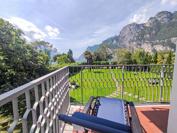 Een balkon met uitzicht op een verzorgde tuin en een bergachtig landschap.