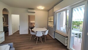A modern interior with a dining area, a kitchen, and a balcony with a view.