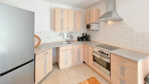 Una cucina moderna con mobili chiari in legno, un forno in acciaio inossidabile e un microonde.