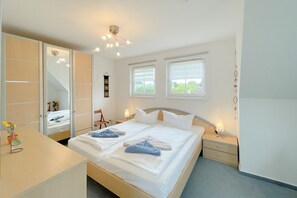 Quarto com cama, mesas de cabeceira, guarda-roupa e espelho.
