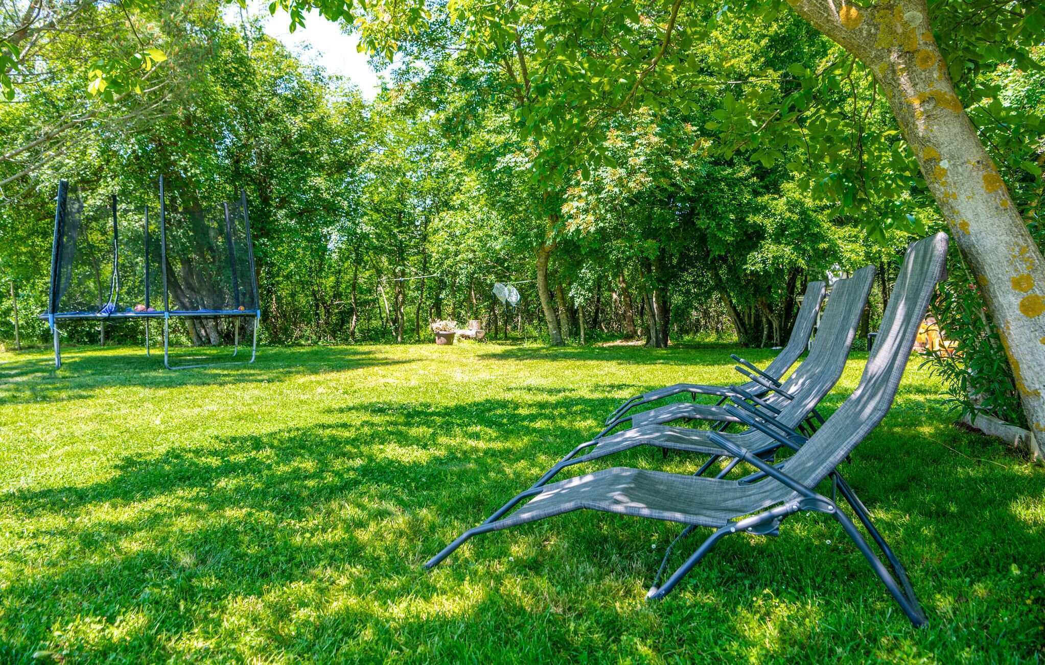 A grassy park area with a metal swing set and a row of metal chairs.