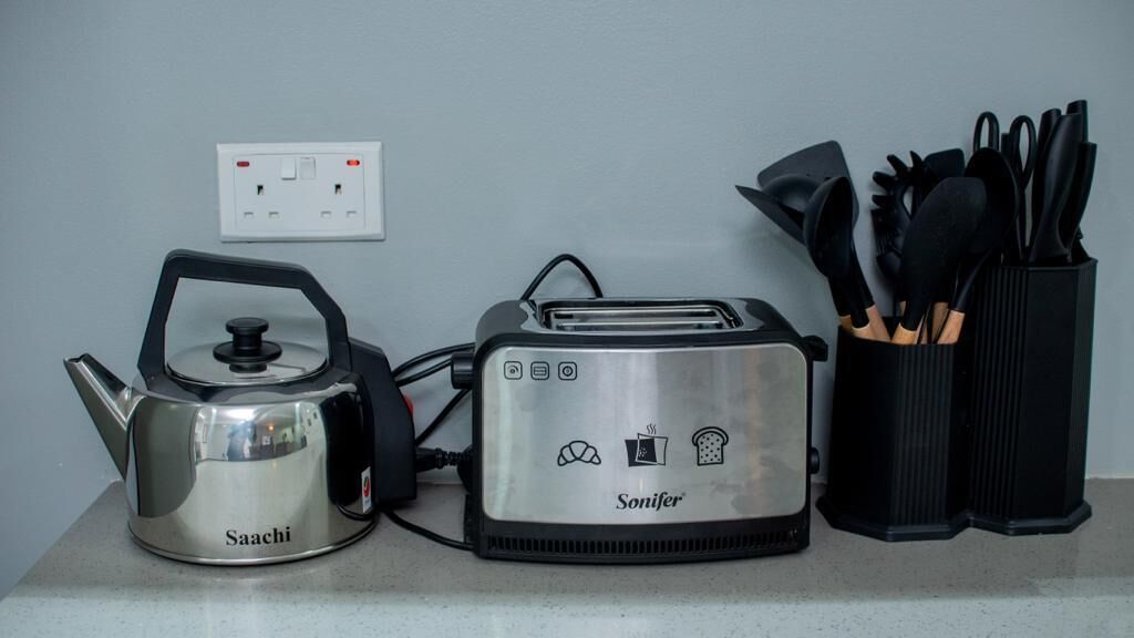 A kitchen counter with a Saachi kettle, a Sonifer toaster, and a utensil holder.