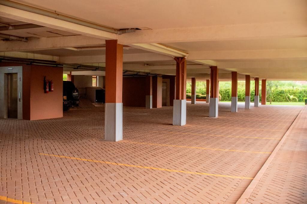 An indoor parking area with brick flooring, concrete pillars, and a fire extinguisher on the wall.