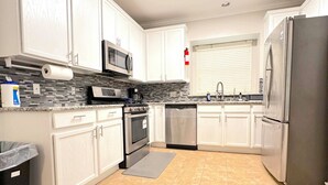 A modern kitchen with white cabinets, a stainless steel refrigerator, a microwave, and a dishwasher. - Spacious 5bed Houston Retreat Home
6 guests 4 bedrooms 5 beds 3 baths (Houston)