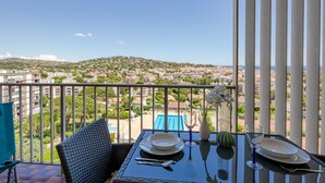 A balcony with a table set for dining, overlooking a cityscape and a hill. - Les Côteaux du Préconil by Interhome (Sainte Maxime)