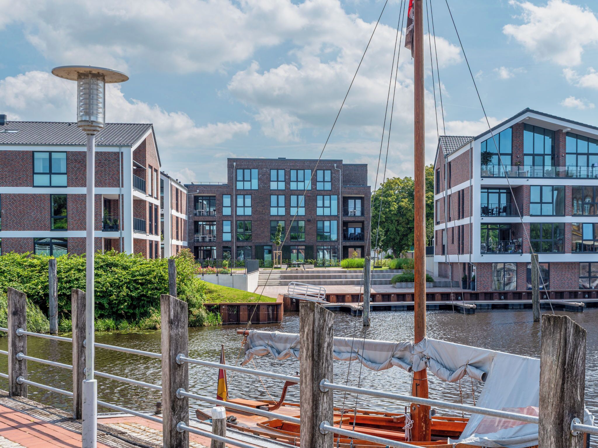 Uitzicht op de rivier met moderne gebouwen, een steiger en een boot, en een heldere lucht.