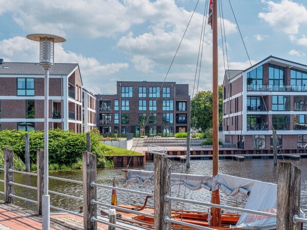 A riverside view with modern buildings, a dock with a boat, and a clear sky.
