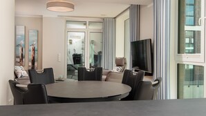 Un espace repas moderne avec une table ronde, des chaises noires et un téléviseur fixé au mur.