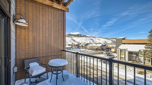 A balcony with wooden paneling, two chairs with snow on them, and a view of a snowy mountain landscape. - Blue River Parkway’s Colorful Escape (Silverthorne)