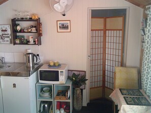 A compact kitchen with a microwave, kettle, and a small dining table.