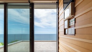 A modern room with a large sliding glass door leading to a balcony with a view of the sea. - VILLA ORCHID (Otaru)