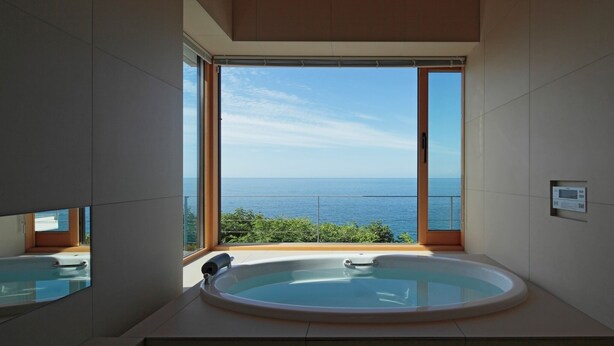 A modern bathroom with a large bathtub and a view of the sea. - VILLA ORCHID (Otaru)