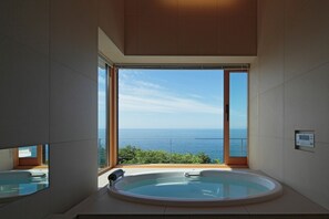 A modern bathroom with a large bathtub and a view of the sea. - VILLA ORCHID (Otaru)