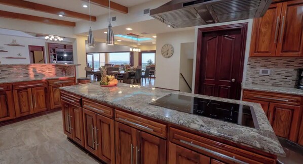 A kitchen with wooden cabinets, granite countertops, a built-in stove, and a dining area with a view.