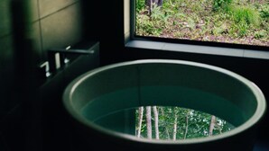 Une baignoire donnant sur une forêt, avec une fenêtre.