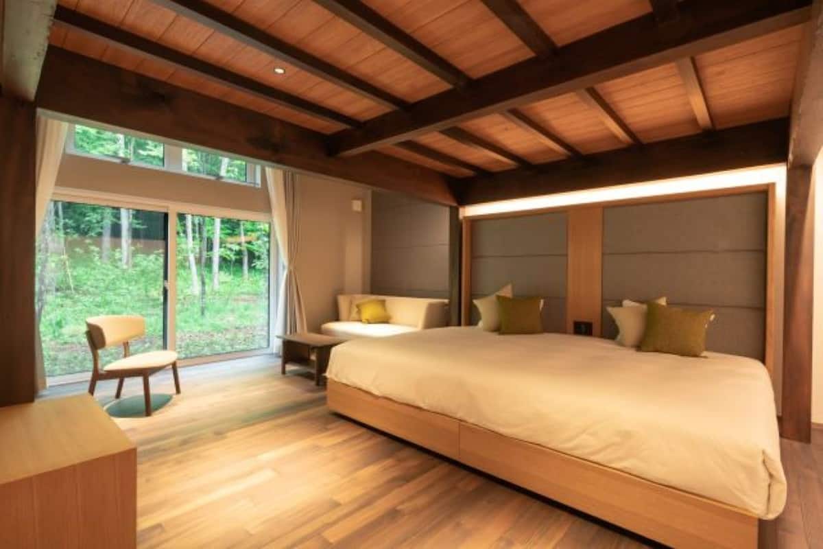 Une chambre avec un grand lit, un bureau, une chaise et une vue sur l’extérieur.