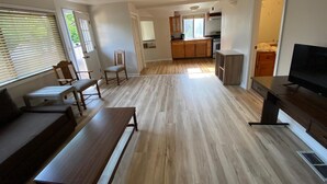 A spacious living area with a wooden floor, a dining table, a sofa, and a TV. - Cozy Amazing Suite  (Willmar)