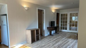 A spacious living area with a wooden floor, a built-in TV stand, and a sliding glass door leading to a balcony. - Cozy Amazing Suite  (Willmar)