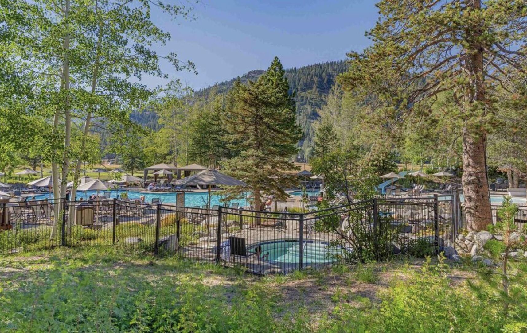 Un complexe hôtelier doté de plusieurs piscines, entouré d’arbres et offrant une vue sur un paysage montagneux.