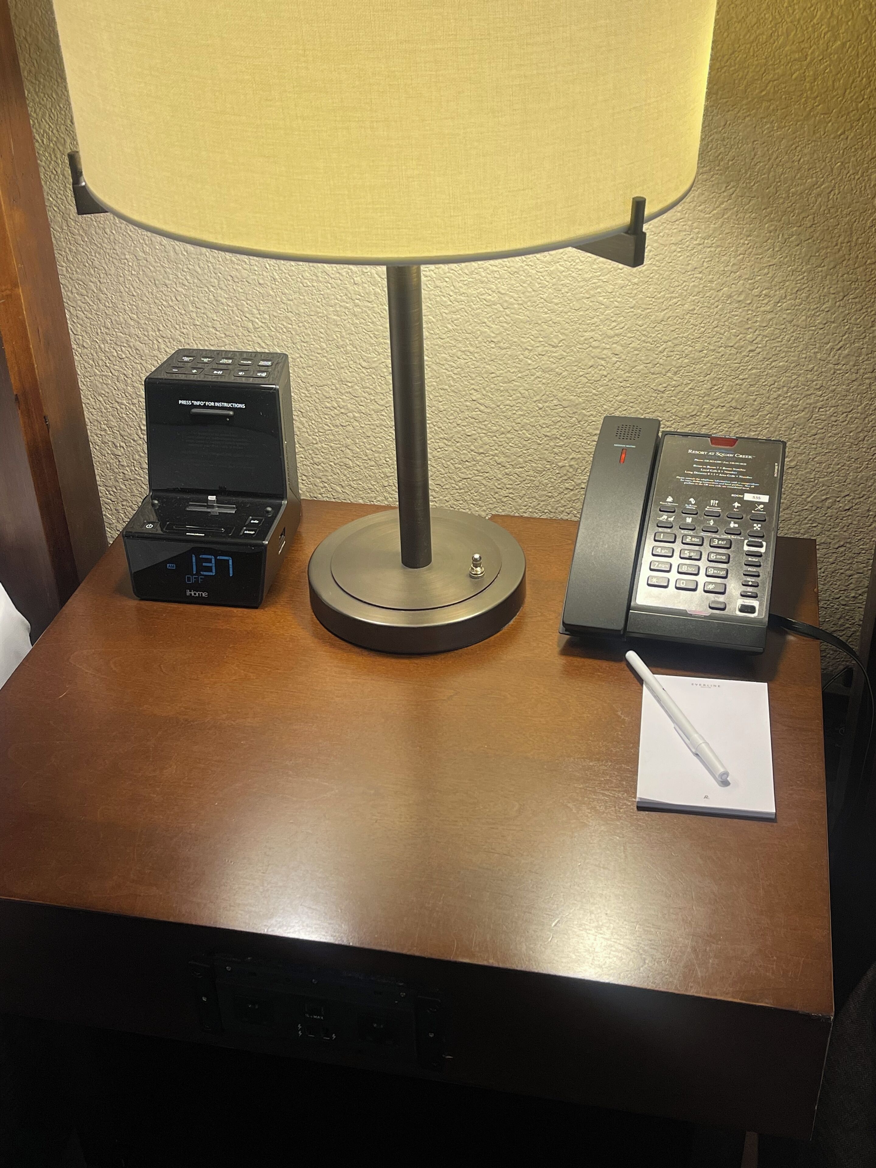 Een bureau met een lamp, een telefoon en een apparaat waarop '137 UIT' staat.