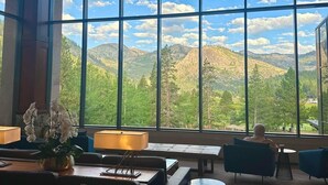Une pièce dotée de grandes fenêtres donnant sur les montagnes, d’un lustre et de meubles modernes.