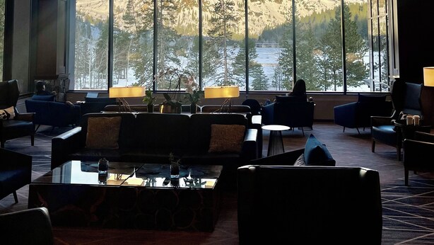 Un hall d’entrée spacieux, doté de grandes fenêtres offrant une vue sur les montagnes, de meubles modernes et d’un lustre.