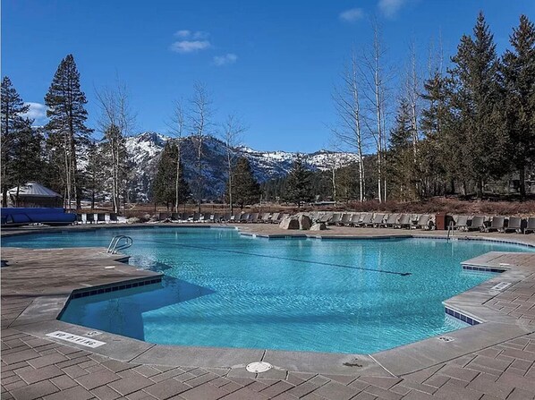 A rectangular swimming pool with clear blue water, surrounded by a paved deck and lounge chairs. - Everline Resort and Spa Forest View (Olympic Valley)