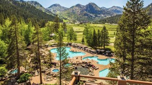 Un complexe hôtelier doté de plusieurs piscines entourées d’arbres, d’un parcours de golf et offrant une vue sur les montagnes en arrière-plan.