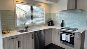 Una cocina moderna con lavavajillas, horno y ventana con persianas.