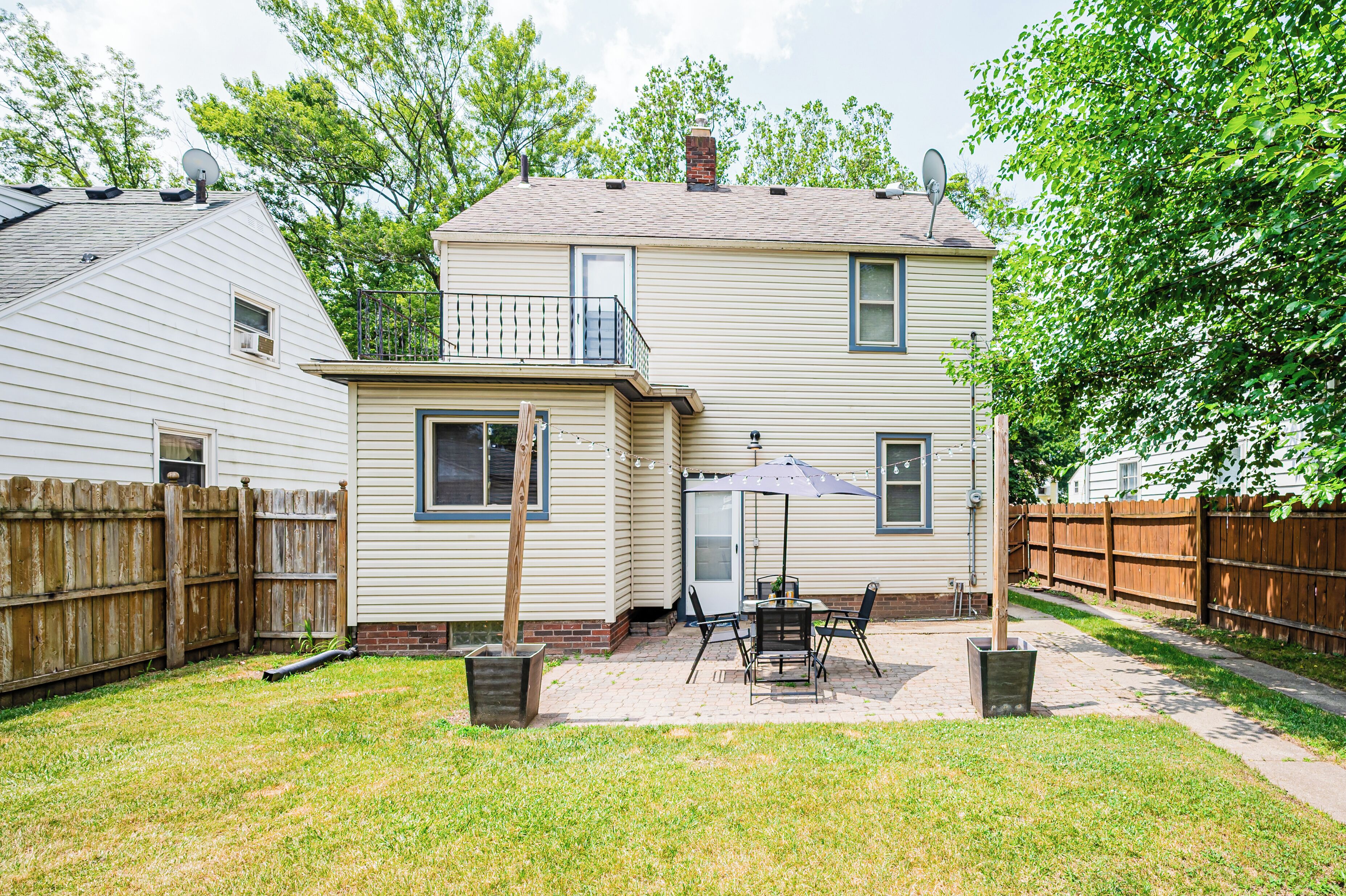 A two-story house with a patio area, a wooden fence, and a satellite dish.