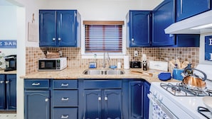 Una cocina con armarios azules, un microondas, un lavamanos y una estufa.