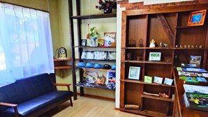 Una habitación acogedora con un sofá de cuero negro, estantes de madera con diversos objetos y un escritorio de madera con libros y adornos.