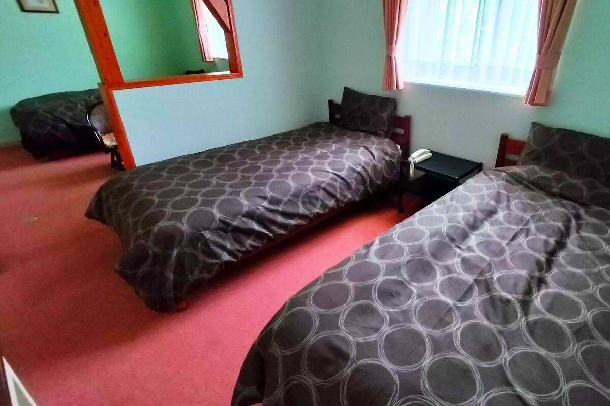 A room with two single beds, a small table, a telephone, and a mirror.