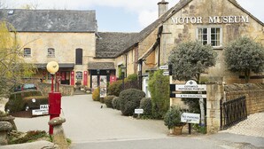 A historic building labeled 'Motor Museum & Toy Collection' with stone architecture, a paved entrance, and signage indicating no parking for residents only.